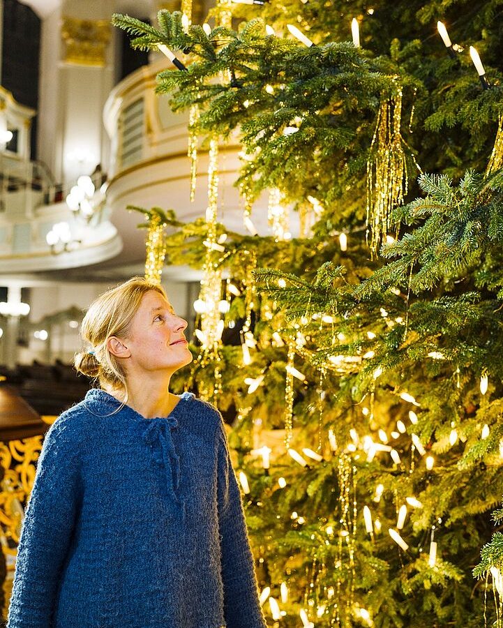 Chorleiterin Gesa Werhahn neben dem Weihnachtsbaum in der Hauptkirche St. Michaelis