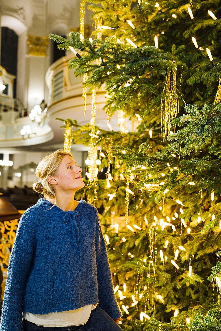 Chorleiterin Gesa Werhahn neben dem Weihnachtsbaum in der Hauptkirche St. Michaelis