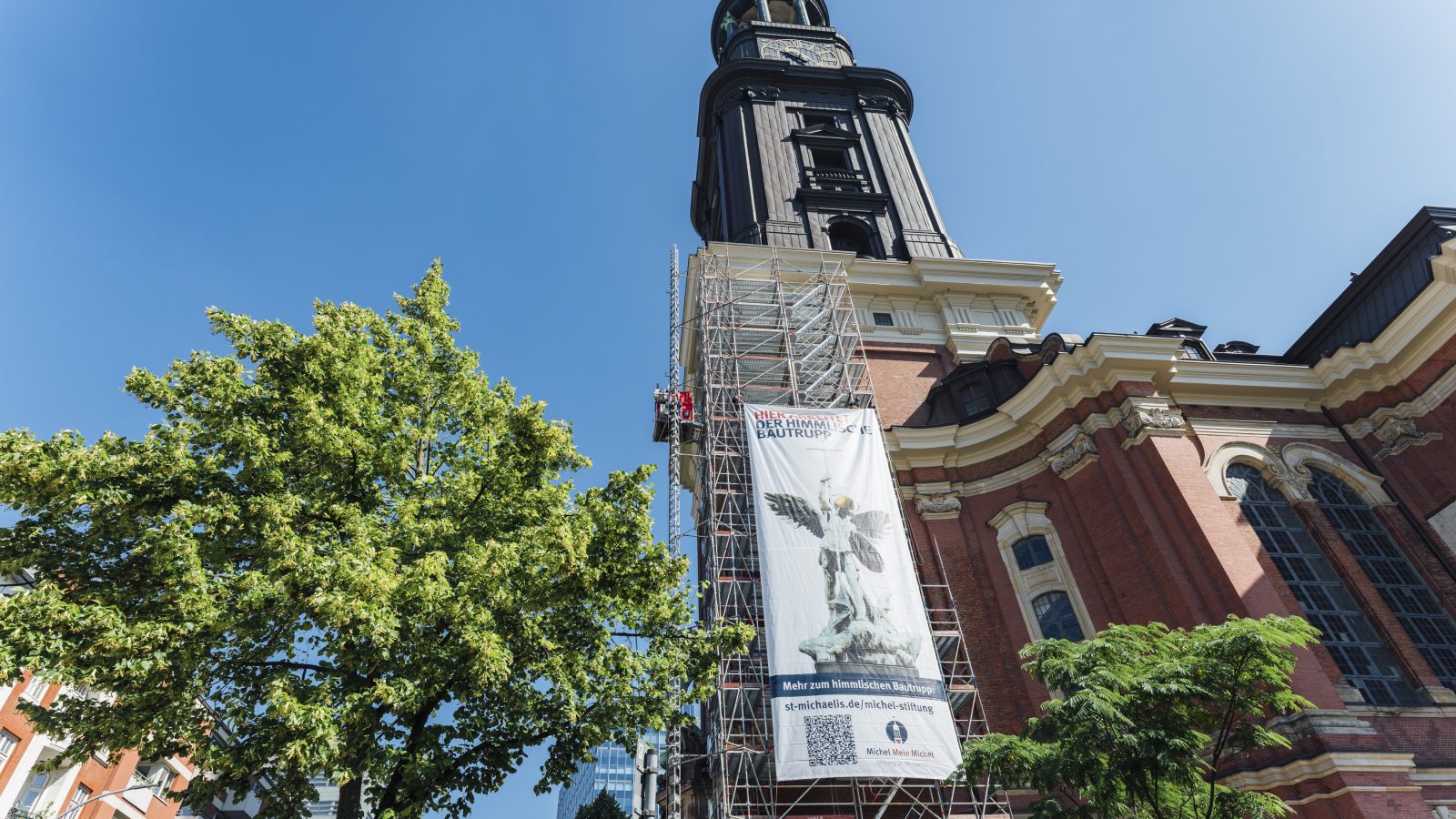 An der Südseite des Michel-Turms ist ein 33 Meter hohes Gerüst mit Banner aufgebaut