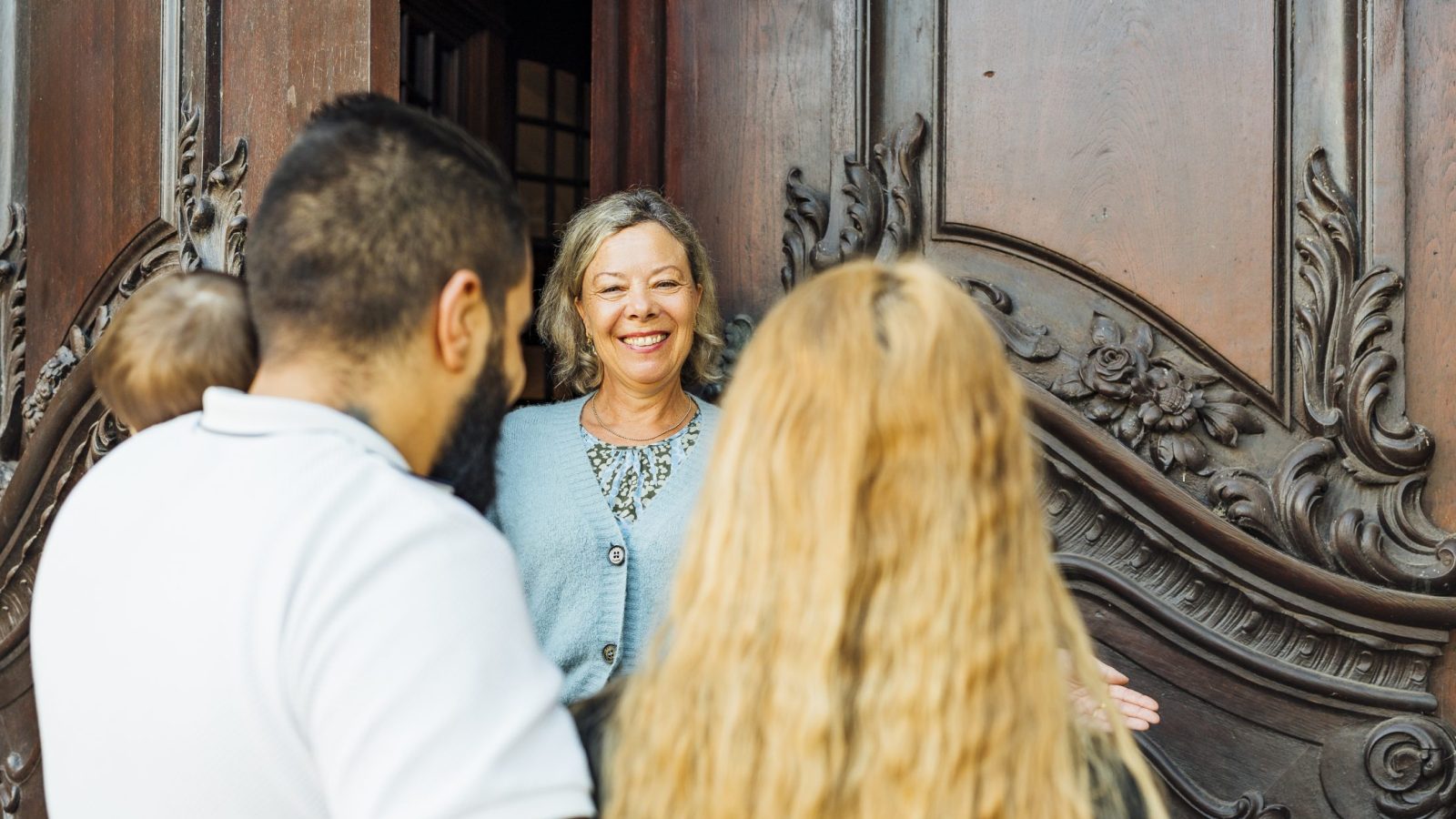 Susanne Gräper begrüßt in der Kirchentür eine junge Familie, die seit sechs Jahren in Deutschland ist und geflohen ist.