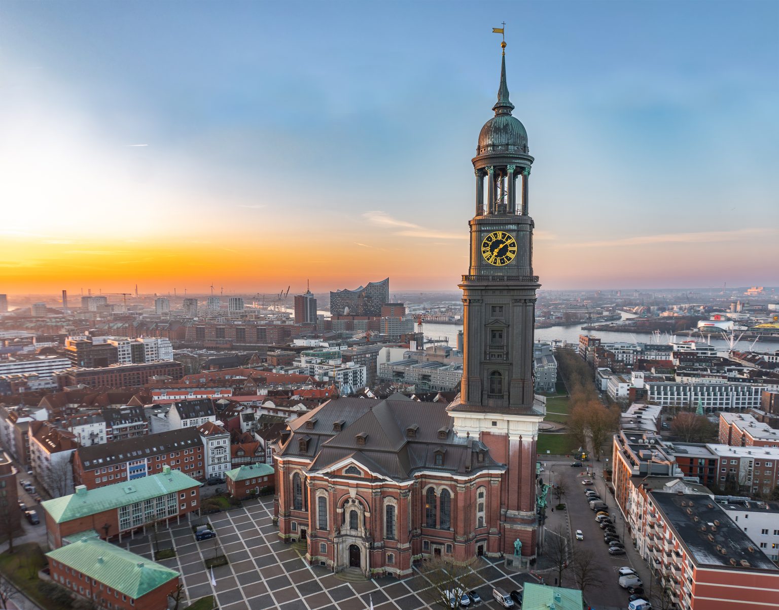 Totalaufnahme des Michel. Im Hintergrund ist die Elbe und der Sonnenaufgang zu sehen.