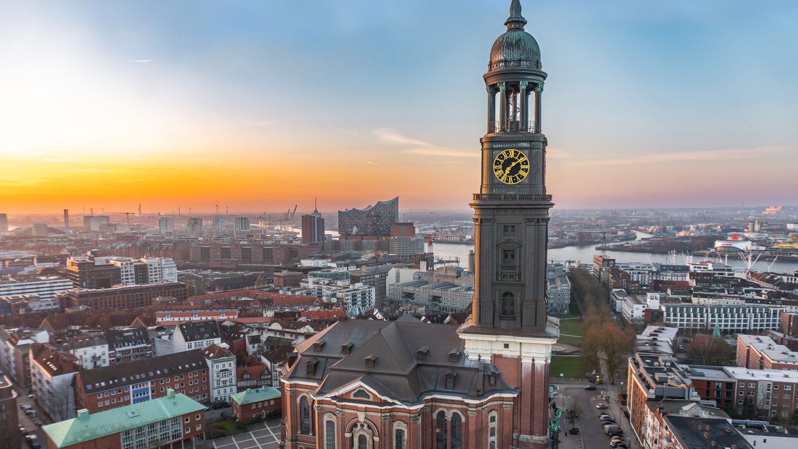 Totalaufnahme des Michel. Im Hintergrund ist die Elbe und der Sonnenaufgang zu sehen.