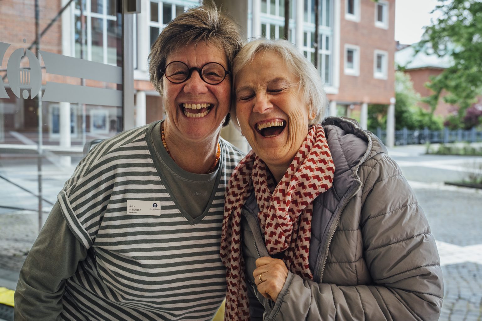 Diakonin Anke Frickmann und eine Teilnehmerin des Michel-Treff lachen fröhlich in die Kamera.