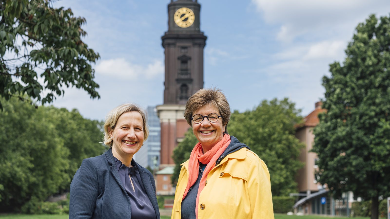 Pastorin Corinna Senf und Diakonin Anke Frickmann auf der Michel-Wiese. Im Hintergrund ist der Michel zu sehen.