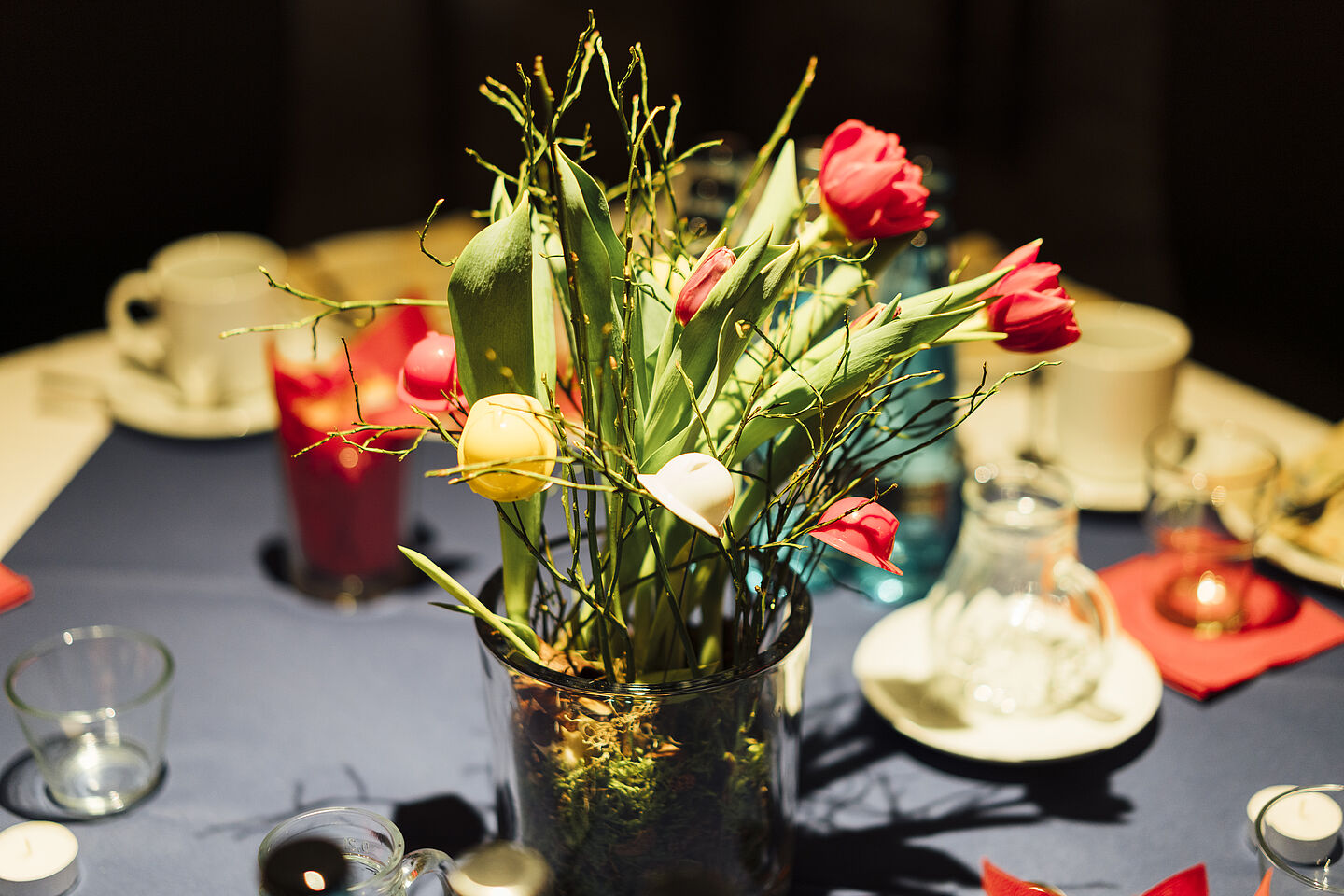 Ein bunter Blumenstrauß in einer Vase auf einem gedeckten Kaffeetisch