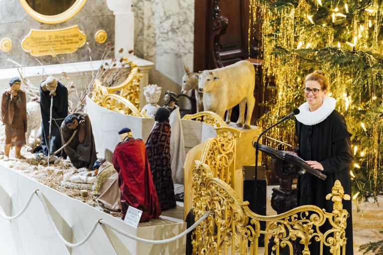 Pastorin Julia Atze steht im weihnachtlich geschmückten Michel neben der Weihnachtskrippe und hält eine Andacht