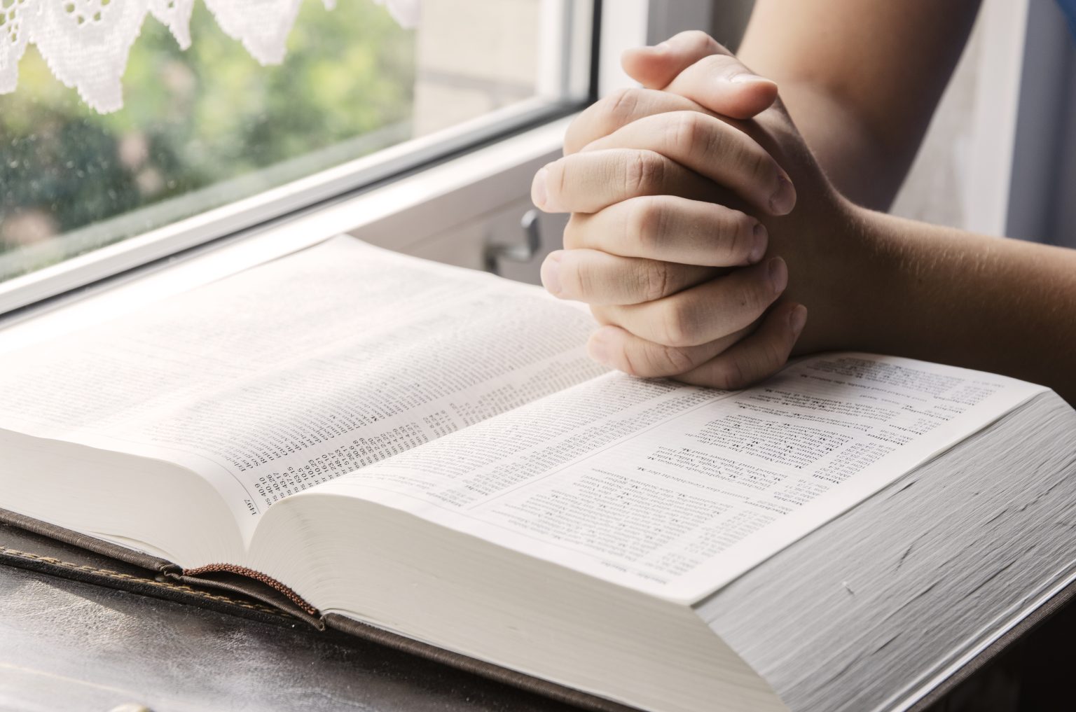Zum Gebet gefaltete Hände auf einer Bibel