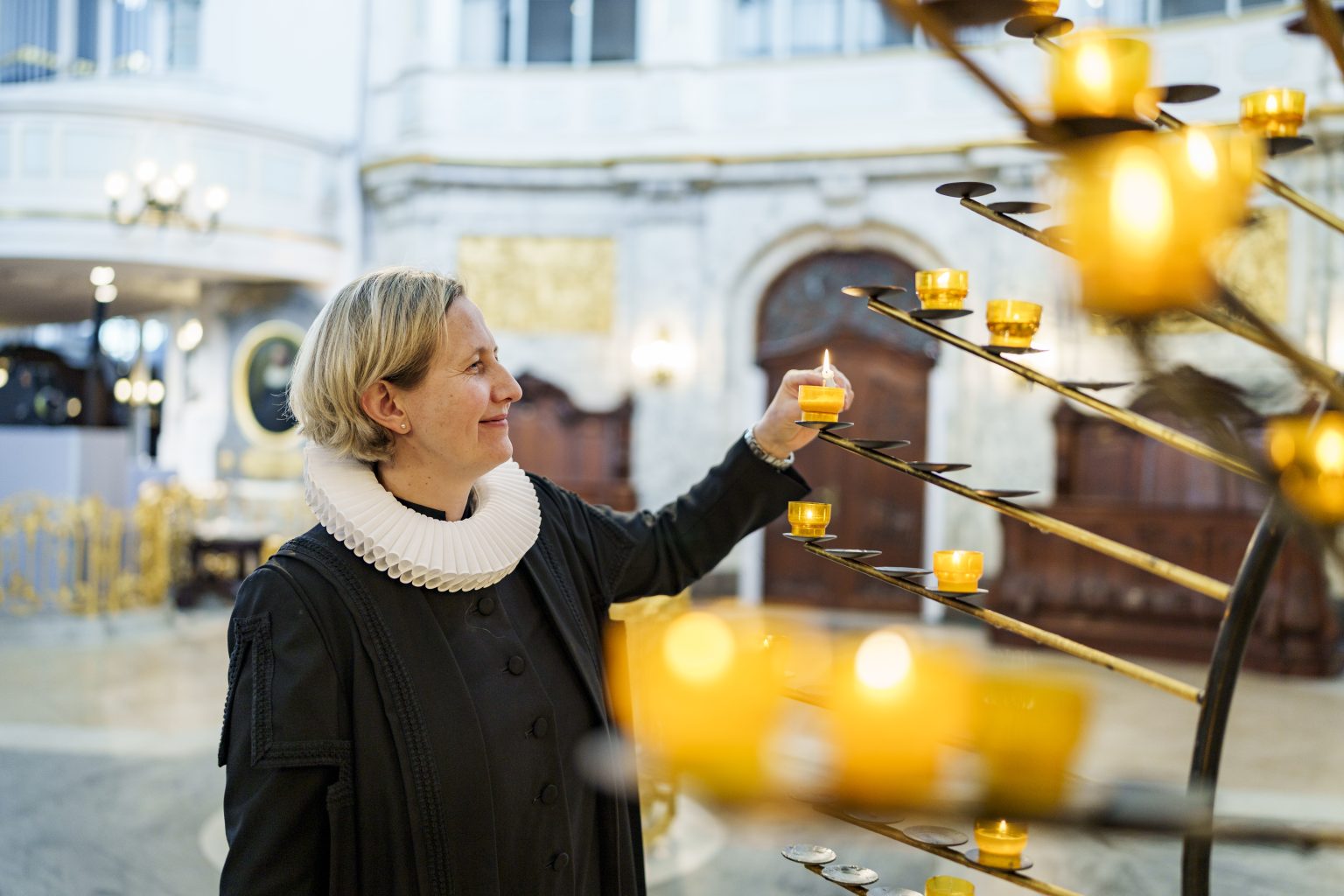 Pastorin Corinna Senf entzündet Kerze am Kerzenbaum