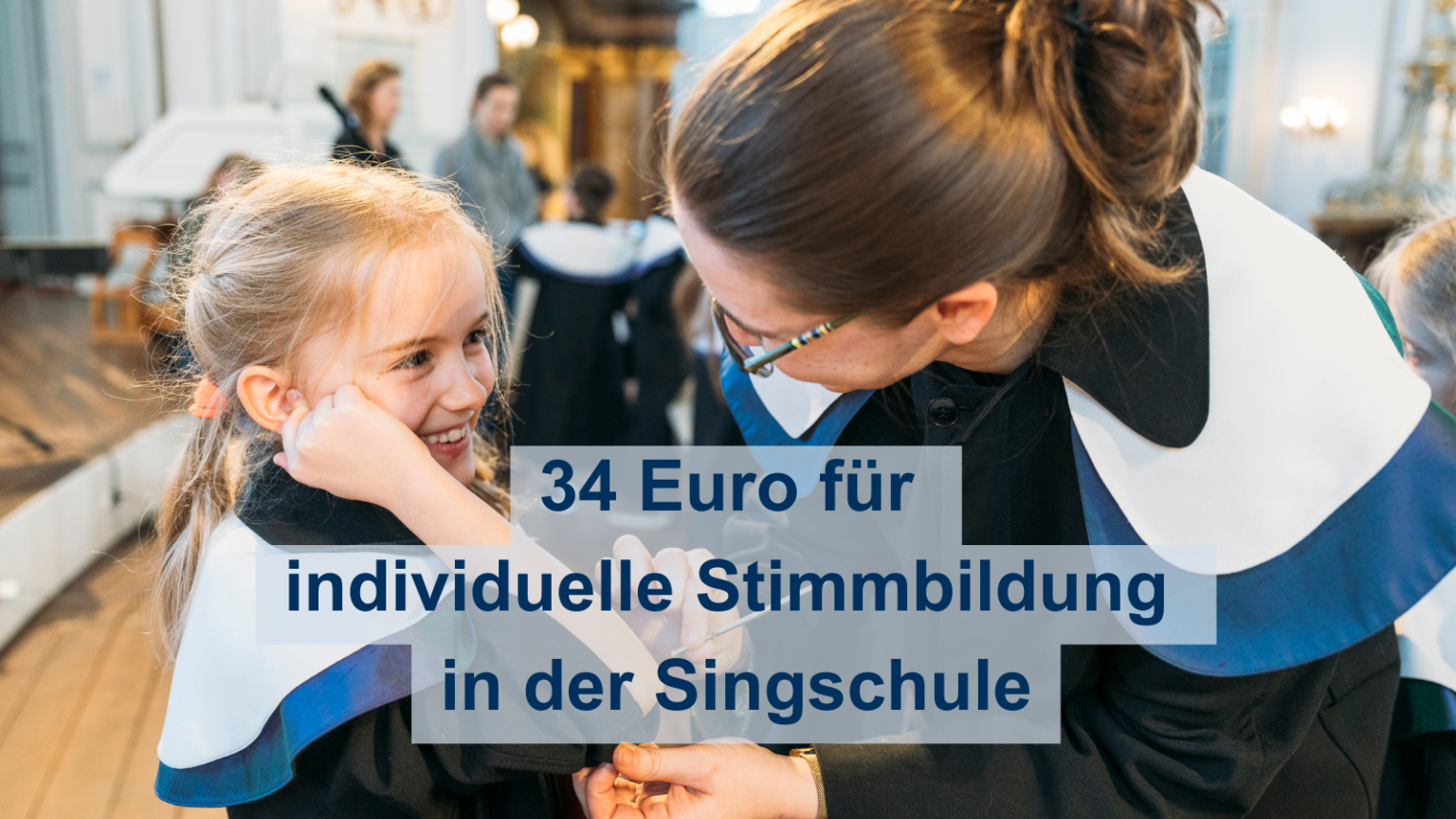 Eine Sängerin der Singschule bekommt von der Leiterin eine Stimmgabel an den Ellbogen getan.