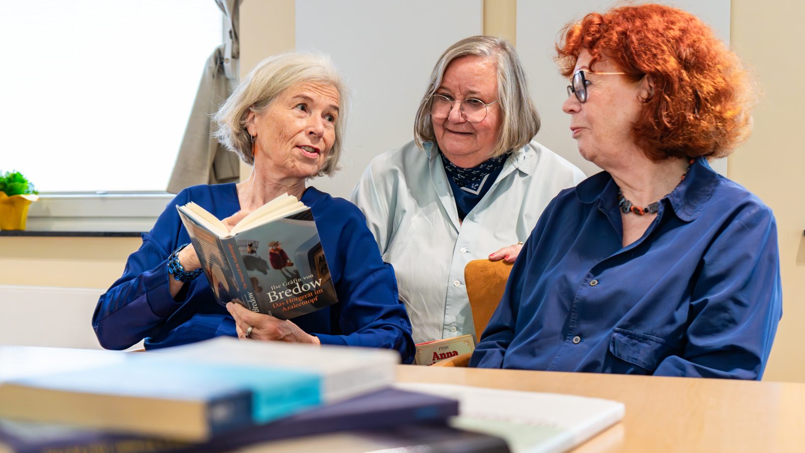 Drei Frauen lesen gemeinsam in einem Buch